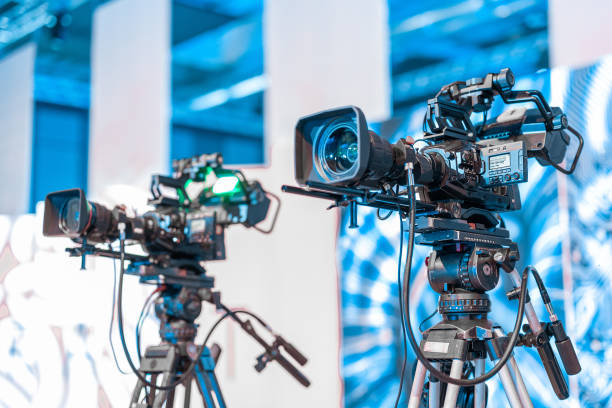 istock Modern 4K broadcast cameras on a tripod. Big camera mounted on stands at a conference or event Live stream ready, professional video stream. 2150923815