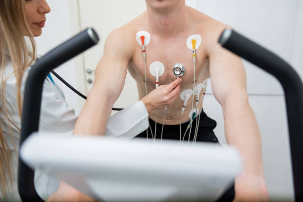 A focused individual performs a stress test on a treadmill, connected to monitoring equipment.