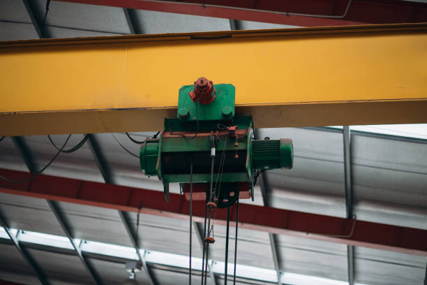 istock A green crane is suspended from a yellow beam 2150925593