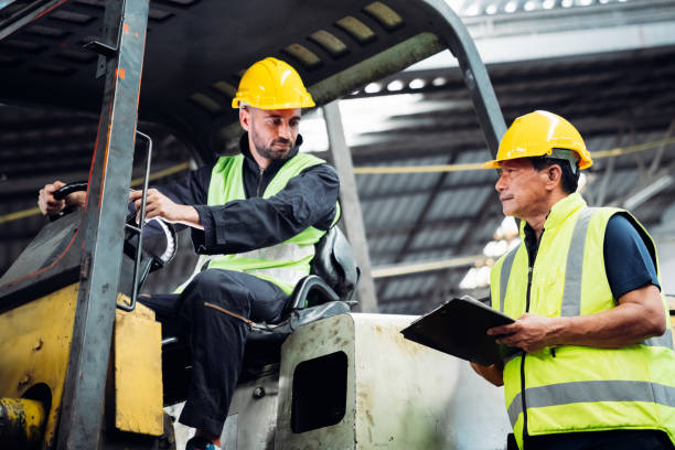 istock Two men in yellow safety vests are standing next to a forklift 2150925994