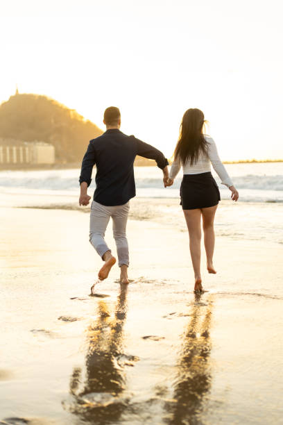 istock Romantic couple playing with sea water running during sunset 2150928045