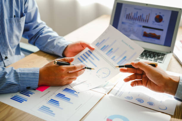 istock Desk-bound businessman calculates figures, verified accounts, and collaborates in discussions. Proficient in using calculators, aiding each other, and managing annual tax accounts in the audit office 2150928376