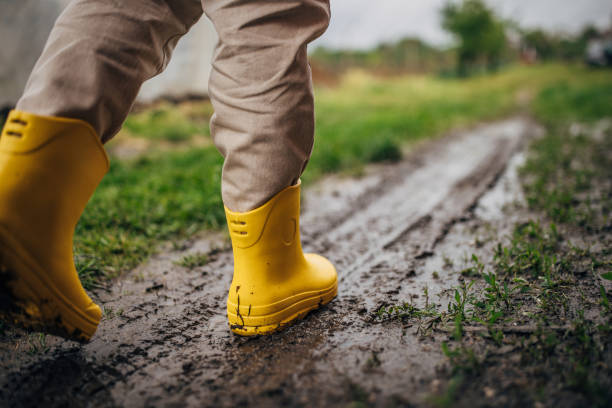 istock Person wearing yellow boots on muddy ground 2150929319