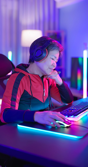 closeup asian elderly female gamer wear headset play online internet cyber sport game at home - she feel frustrated after losing