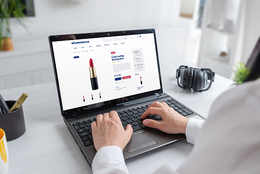 Woman purchases long-lasting red lipstick online from cosmetics store using laptop. Effortless beauty shopping for bold, vibrant lips