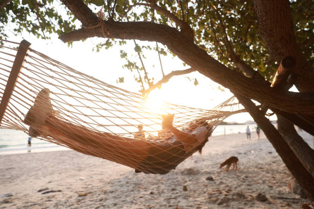 Selective focus on the girl on the white hammock and the shadow on a sandy beach on a sunny day, a family vacation concept.