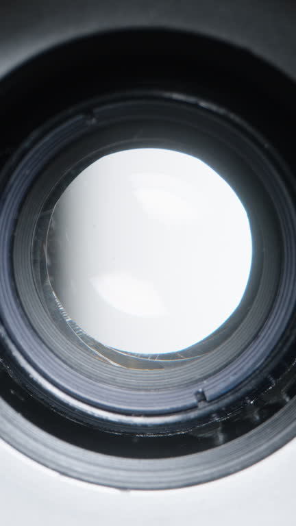 Vertical video. Diaphragm aperture smoothly widens, macro view inside the optical device.