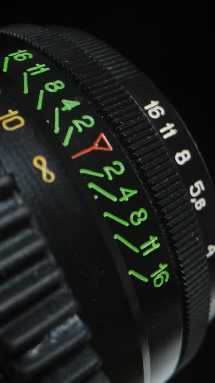 Vertical video. Close-up, male hands turn the focus ring of the lens, with engraved markings on it.