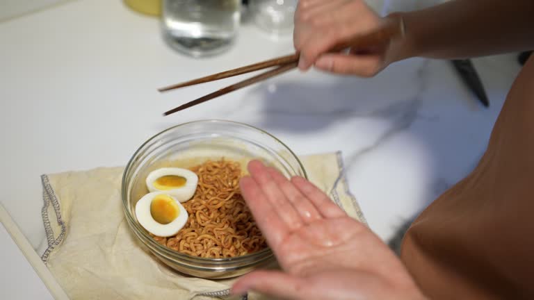 Close up hand adding egg slice into the ramen bowl