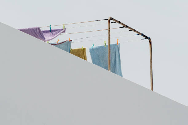 Partial view of towels on a clothesline on a roof terrace of a Mediterranean house facade against a blue sky
