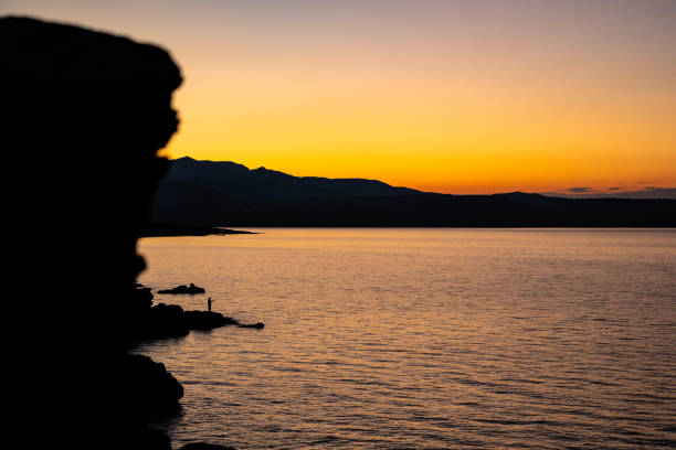 A fisherman throws his fishing rod into the sea at sunset off the coast of Lesbos, Greece, near the city of Mytilene, June 2, 2020, amid the outbreak of the coronavirus and quarantine. Many islanders earn their living by fishing in the waters of the Aegean Sea.