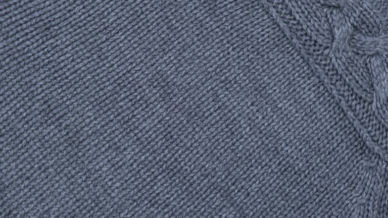 Soft Knitted Woolen Detailed Texture. Natural Fabric Closeup Knit Pattern. Gray Knitwear, Warm Cashmere Surface. Rotation, Macro. Cozy Creamy Textile Background. Clothes Production. Melange Yarn. 4K
