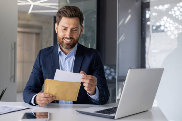 Smiling businessman opening an envelope at his desk
