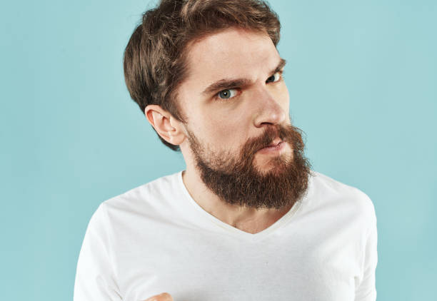 istock Model bearded man in white T-shirt on blue background irritability emotions model 2150957122