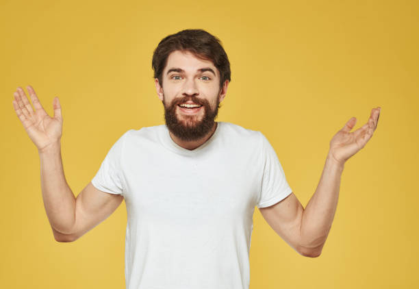 istock A man in a white T-shirt gestures with his hands on a yellow background Copy Space 2150957849