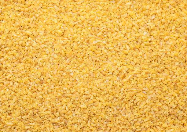 Yellow raw organic healthy bulgur grain seeds textured background.