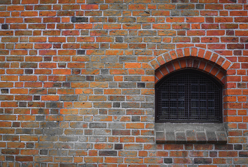Old brick wall with an arched window.