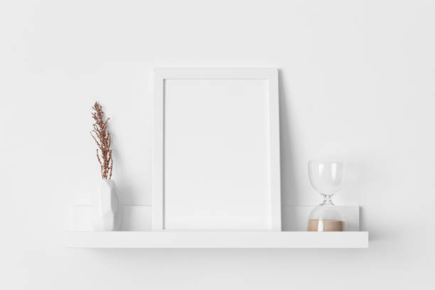 istock White frame mockup with a dry flower decoration on the wall shelf. 2150964730