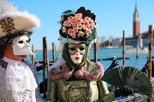 People in traditional costumes and masks outdoors during the famous Venice Carnival in Italy