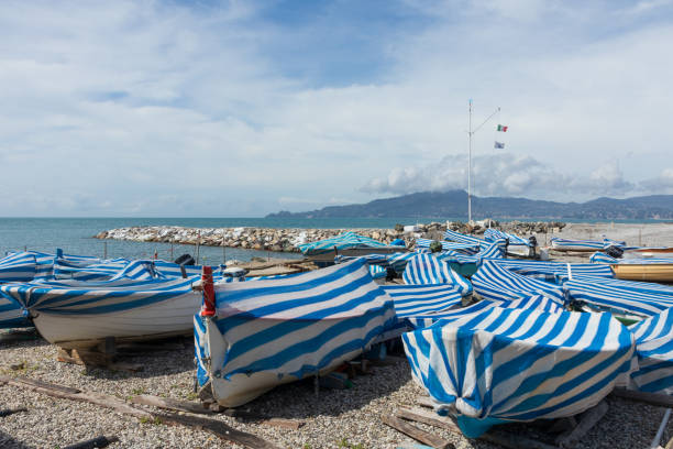 Chiavari, Italy - April 05 2024 - Numerous boats covered with blue and white sheets color Chiavari's waterfront where Portofino and the Tigullio gulf can be seen in the background