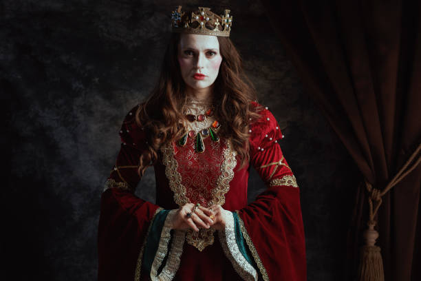 istock medieval queen in red dress with white makeup and crown 2150965978