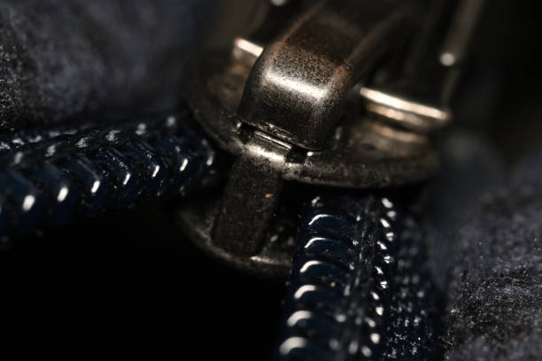 A detailed shot of a blue jacket's zipper, showing the metal pull and the teeth, with the fabric's texture.