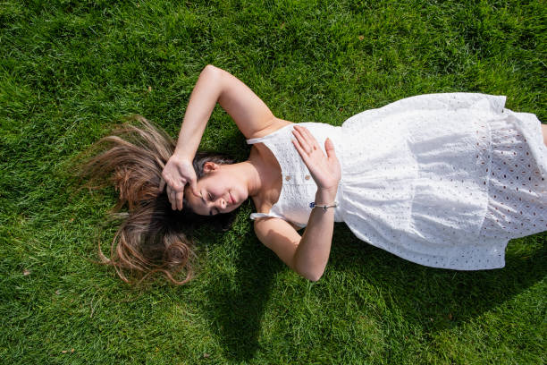 istock pretty young woman lying on green grass 2150978354