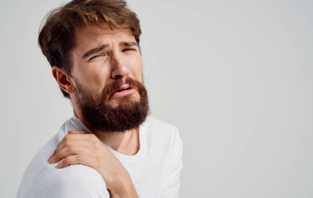 istock bearded man touching shoulder with hand pain dislocation 2150980081