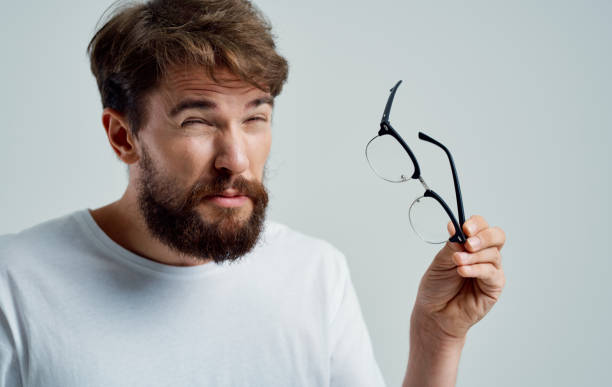 istock vision problems man holding glasses in hand pain in the eyes gray background 2150982127
