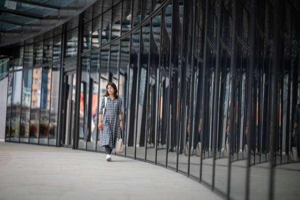An Asian Chinese tourist caring a shopping bag and walking on the street at elevated pedestrian walkway in city