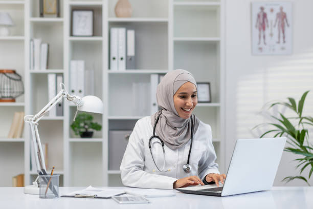 istock Muslim female doctor working happily on computer in clinic 2150984096