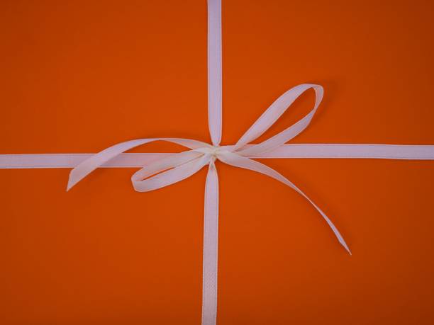 istock A white bow on an orange paper background. 2150984308