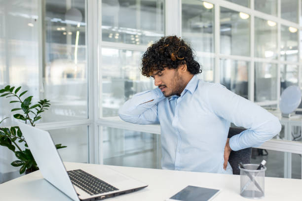 istock Young man experiencing back pain while working at his office desk 2150984928