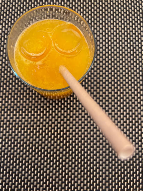 A black cup holding a drink sits on a flat surface with a white straw protruding, set against a soft, warm-toned background