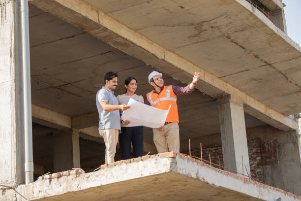 istock Architect explaining blueprint to couple at construction building 2150990140