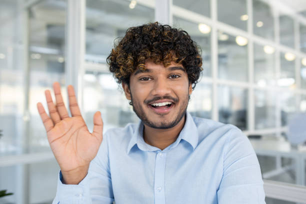 istock Cheerful young man waving hello in modern office setting 2150991245
