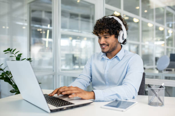 istock Young professional with headphones working on laptop in office 2150993503