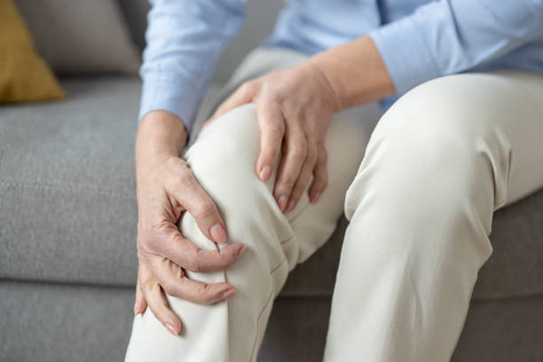 istock Senior woman holding her aching knee at home 2150995401