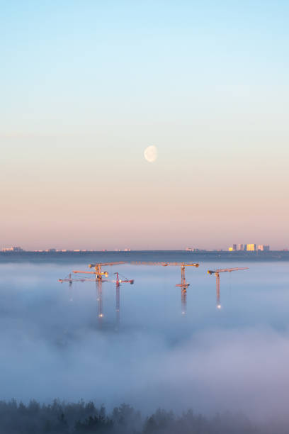 Tower cranes at construction site in the morning fog
