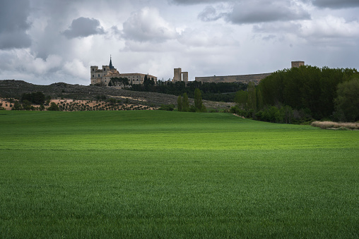 Landscape in Uclés with the monastery and castle in the background surrounded by green fields, Cuenca, Spain