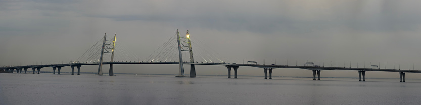 Panoramic view: high cable-stayed bridge over the bay in the evening twilight