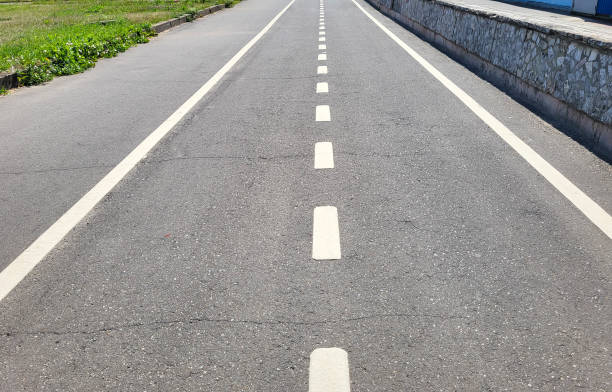 Grey asphalt treadmill or bike path with white markings