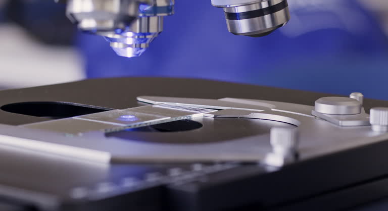 Inserting slide under lens of laser microscope in laboratory
