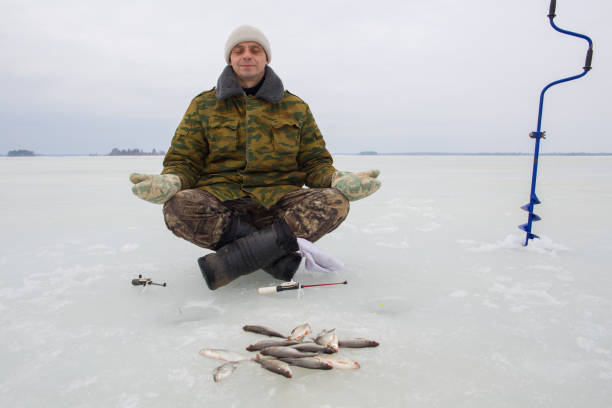 Fisherman pulling a fishing net filled with caught fish from a frozen lake during winter, surrounded by snow-covered landscapes in siberia, russia, capturing the essence of ice fishing