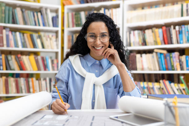 istock Architect reviewing blueprints in library with joyful smile 2151003309