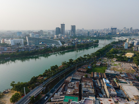 A stunning aerial panoramic view of the Dhaka cityscape skyline during sunset. The metropole commercial areas and modern skyscrapers are beautifully illuminated against a cloudy sky. Perfect for urban-themed projects. Drone View of Dhaka Cityscape. Dhaka Elevated Expressway with residential buildings and corporate building in Dhaka