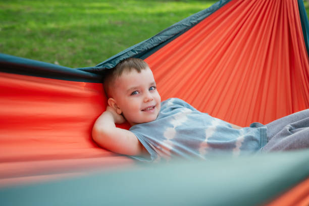 istock Cute joyful boy playing in the hammock outdoors 2151004712
