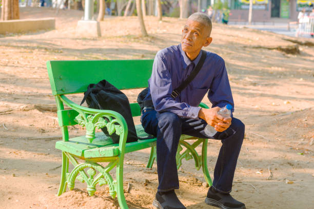 Thai senior man sitting on a bench in park