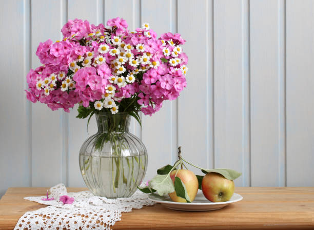 istock phlox and daisies on the table in a vase and apples. 2151005284