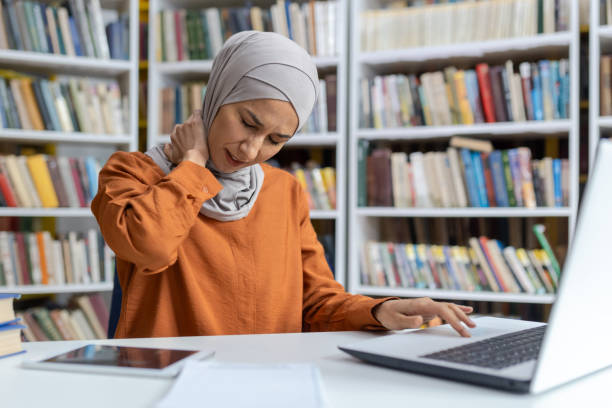 istock Young woman feeling neck pain while working in library 2151006404